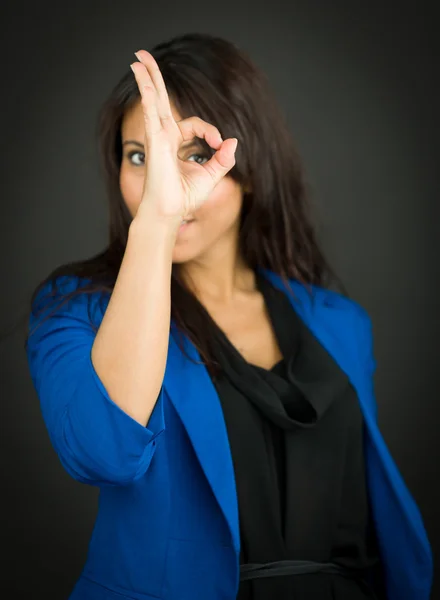 Porträt einer jungen Geschäftsfrau, die durch ein Loch in den Fingern blickt — Stockfoto