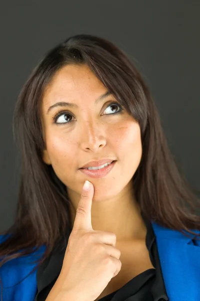 Nachdenkliche junge Geschäftsfrau, die mit dem Finger am Kinn nach oben schaut — Stockfoto