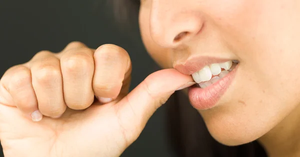 Extremo primer plano de una joven mordiéndose las uñas y sonriendo —  Fotos de Stock