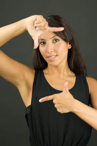 Mujer joven confiada haciendo marco con los dedos y sonriendo — Foto de Stock