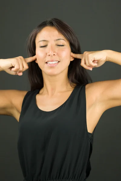 Smiling young  woman standing fingers in ears — Stock Photo, Image