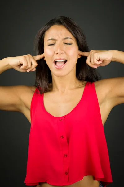 Young woman shouting in frustration with her fingers in ear — Stock Photo, Image