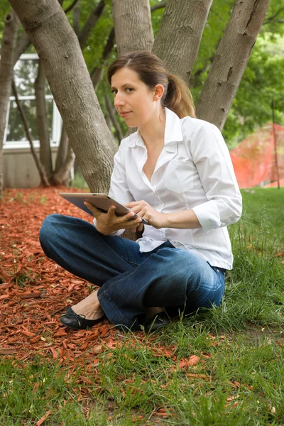 Vrouw in park met digitale tablet — Stockfoto