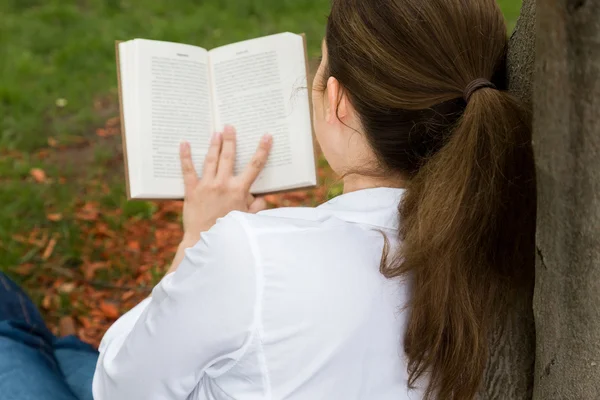 Vrouw in park lezen van een boek — Stockfoto