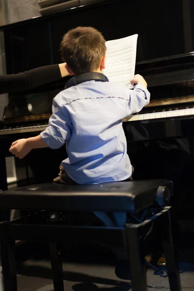 Bakifrån av en liten pojke lärande piano från instruktör — Stockfoto