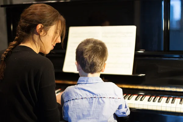 Bakifrån av en liten pojke lärande piano från kvinnliga instruktör — Stockfoto