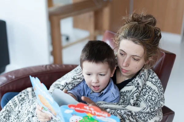 Petit garçon et sa mère lisant un livre d'histoire ensemble à la maison — Photo