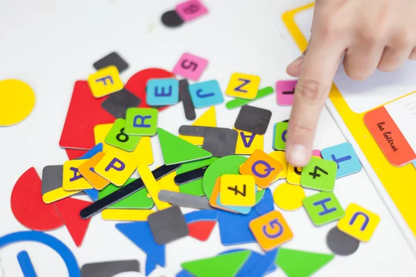 Nahaufnahme einer Personenhand mit mehrfarbigen Buchstabenpuzzleteilen — Stockfoto