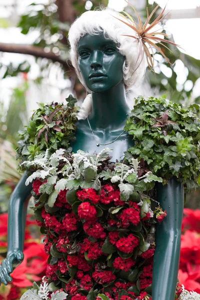 Statue in clothes made of red Christmas flowers — Stock Photo, Image