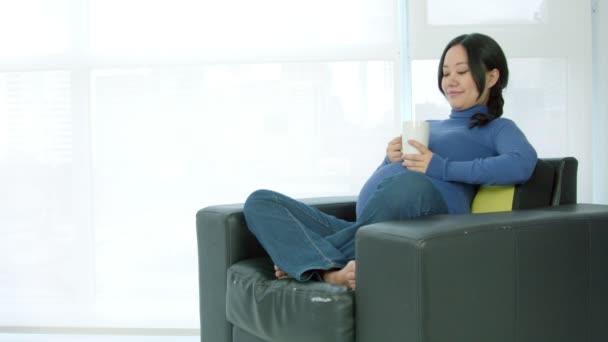 Femme enceinte assise dans un canapé — Video