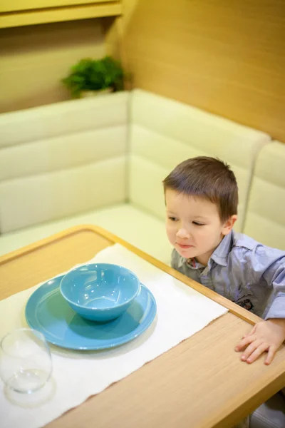 Hög vinkel syn på en liten pojke på ett matbord i en yacht — Stockfoto
