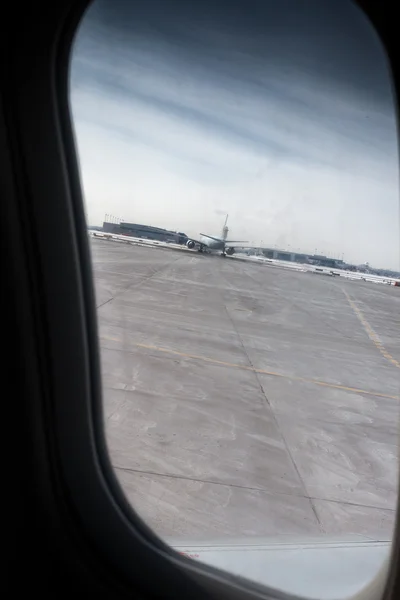 Parked airplane at an airport seen through airplane window