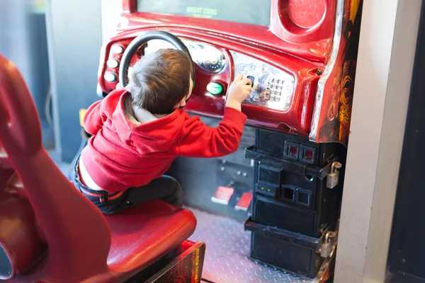 Achteraanzicht van een jongen spelen driving spel bij de arcade van de video game — Stockfoto