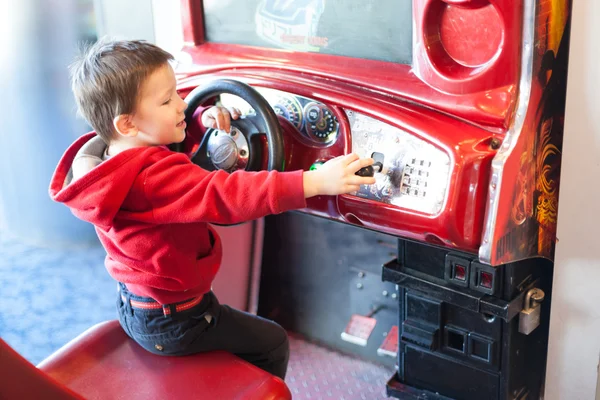 Küçük bir çocuk video oyun arcade sürüş oyunu oynarken yan görünüm