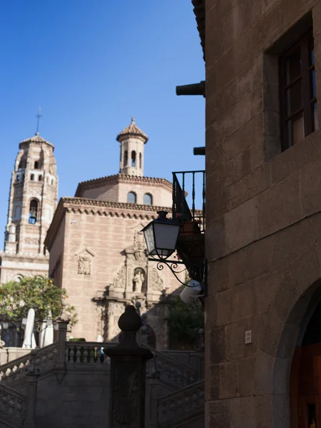 Low angle view of a lantern at building with a clock tower in the background, Utebo Clock Tower, Poble Espanyol, Barcelona, Catalonia, Spain — Stock Photo, Image