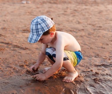 Kumsalda oynarken sevimli küçük çocuk 