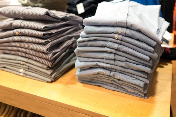 Pilhas de camisas na loja de roupas — Fotografia de Stock