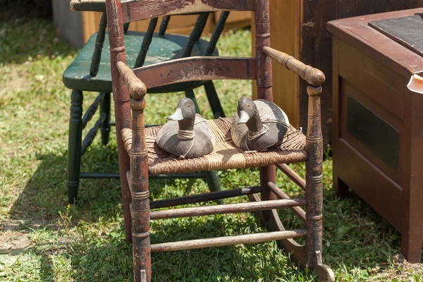 Две деревянные утки на стуле на продажу — стоковое фото