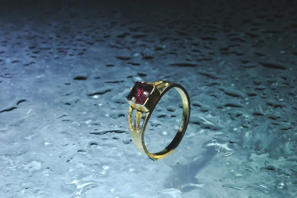 与 raindroped 的蓝色背景上的红宝石金戒指 — 图库照片