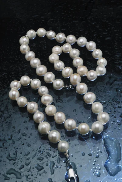 Collana di perle sdraiato su sfondo blu acqua caduto — Foto Stock