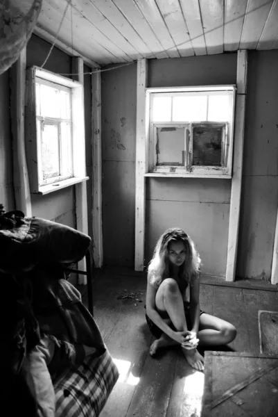 Chica triste sentado en el suelo en una habitación pequeña en blanco y negro — Foto de Stock