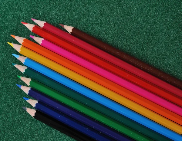 Set of multicolored pencils on green texture background