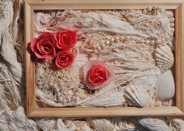 Rosa, marco de madera, perlas y conchas en el fondo de los hilos — Foto de Stock
