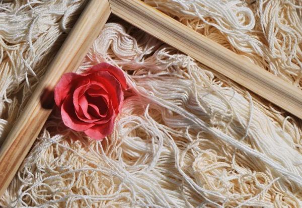 Rose and wooden frame on threads background — Stock Photo, Image