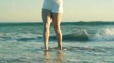 Genç bir kadın sahilde yürüyor.