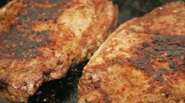 Tavada dönen iki parça biftek.