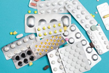 Mavi arkaplanda tablet şeklinde farklı haplar var. Tedavi için ilaç reçetesi. Eczane.