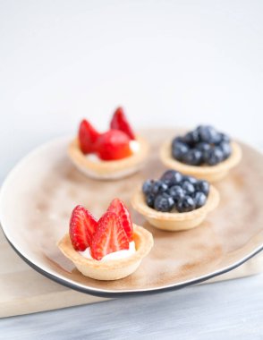 Peynir kremalı kek, taze böğürtlen ve ahşap bir arka planda bej bir tabakta yabani böğürtlen. Yemek tarifleri ve tatlılar için bir fikir. Mükemmel parti bireysel taze meyve tatlısı..