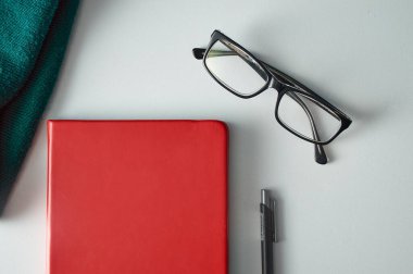 Okuma merceği ve beyaz masa üzerinde siyah mekanik kalem ile dikey kapalı kırmızı defter