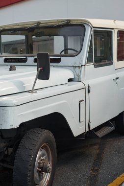 Büyük, uzun, beyaz, park edilmiş, geniş lastikli, eski pencereli bir karavan.