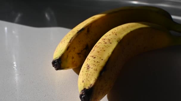 Twee Gele Bananen Met Zwarte Vlekken Zon Een Schone Witte — Stockvideo