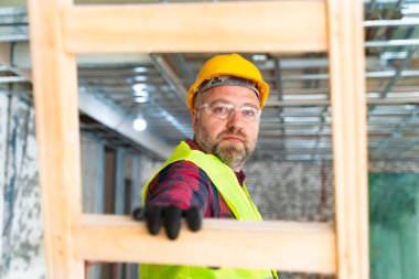 İnşaat alanının duvarını alçılayan malayla çalışan alçı adam.