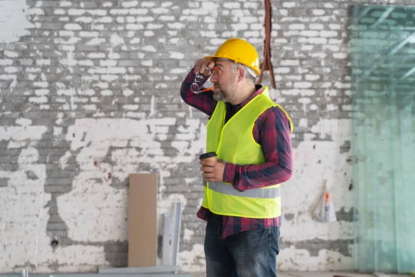 construction worker analyzing plans during coffee break in a workshop