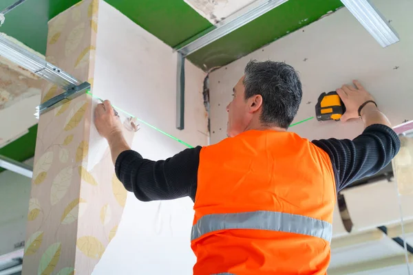 in working with on a ladder  at the construction site indoors construction worker measuring support beam