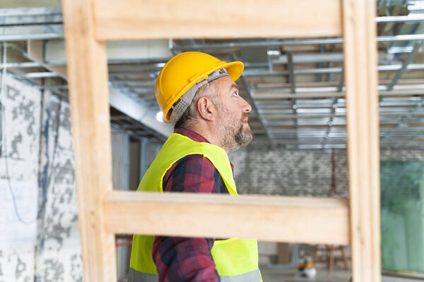 Plasterer man at work with trowel plastering the wall of interior construction site