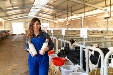 Farmer standing with two bottles of fresh milk in hands on farm