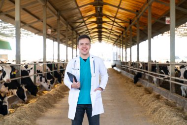 cheerful veterinarian standing with digital tablet in barn