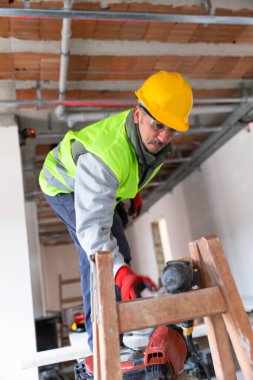 İşçi elektrikli matkabı alıyor. 