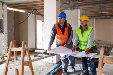 İnşaat mühendisleri inşaat alanındaki planlara birlikte bakıyorlar.