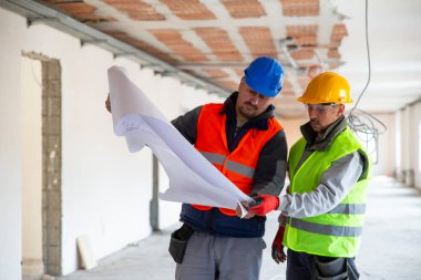 İnşaat işçilerinin planlarını gözden geçirdikleri yakın plan.