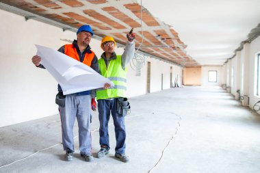 İşçi binanın tavanını ustabaşına gösteriyor.