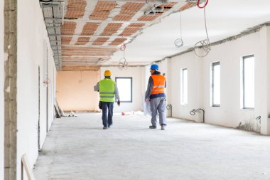 İnşaat alanında yürüyen iki elektrikçi mühendis işçisi