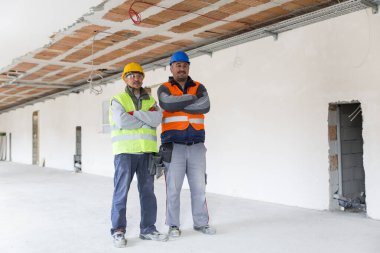 İki inşaat işçisi yeni inşaat sahasına bakıyor.