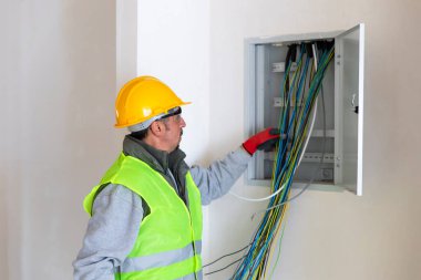 Elektrik panelinde renkli kabloları tutan elektrikçi. 