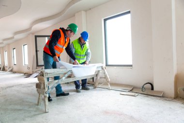 Mühendis binanın planlarını gösteriyor.