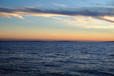 Güneş ışığının okyanus yüzeyindeki çıplak tonlarının yansımasıyla mavi okyanus günbatımı.